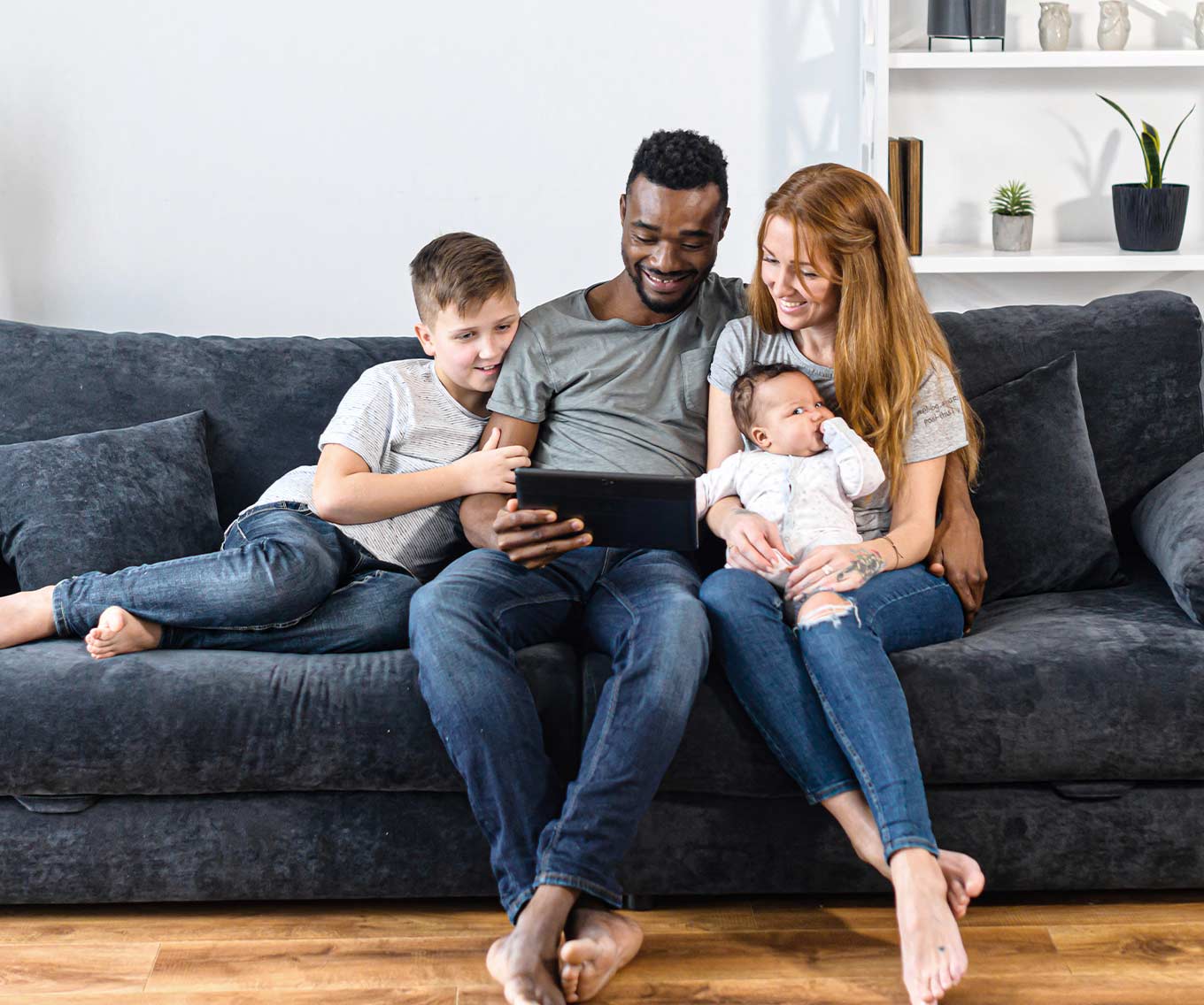 Family sitting on a couch looking to purchase a house.