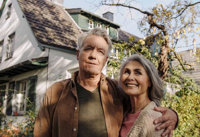 Couple in front of suburban home considers their cash-out refinance home equity.