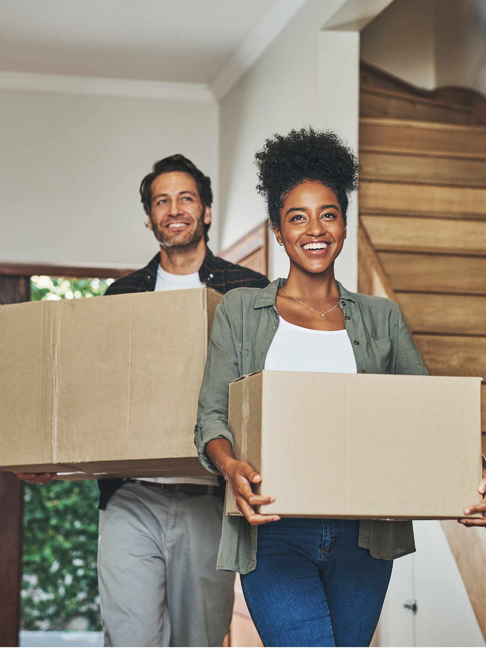 Couple carries moving boxes into their new home purchased with a conventional loan.