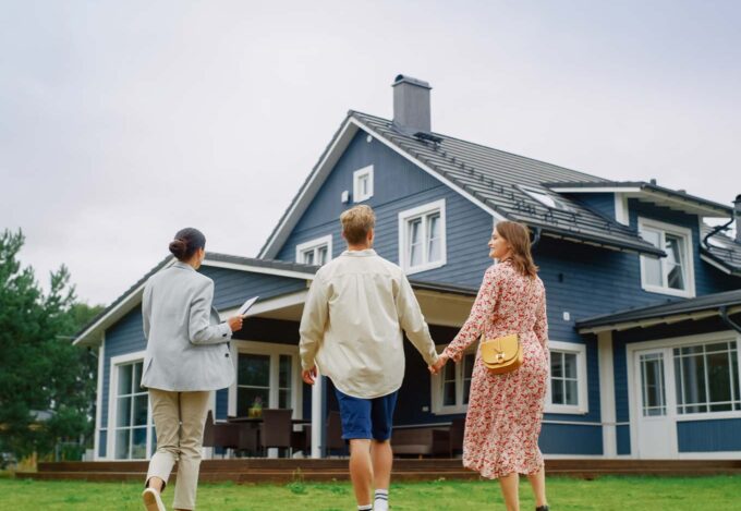 Couple tours outside of house for sale with their real estate agent.