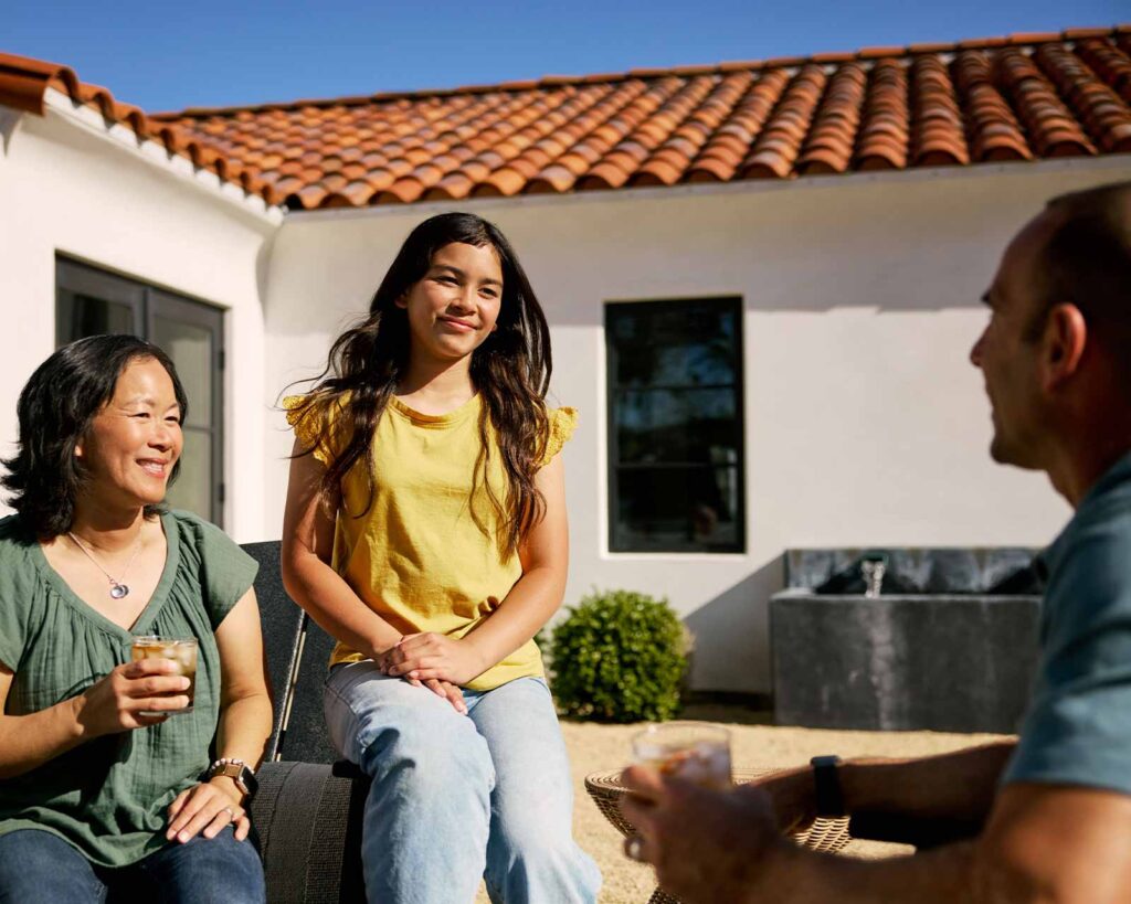 Family sits together on back porch outside of home discussing mortgage pre-approval.
