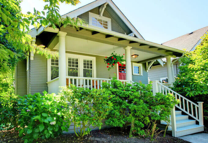 A craftsman-style house with a red front door and green yard, representing a typical home a buyer might purchase with an FHA loan.