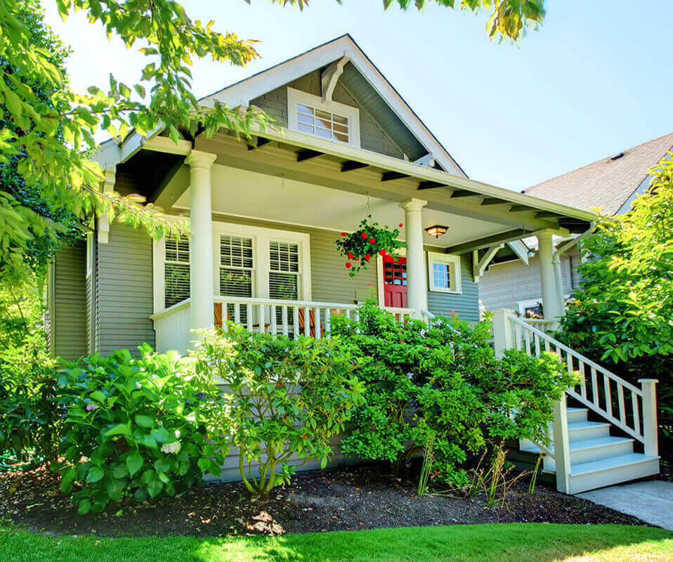 A craftsman-style house with a red front door and green yard, representing a typical home a buyer might purchase with an FHA loan.