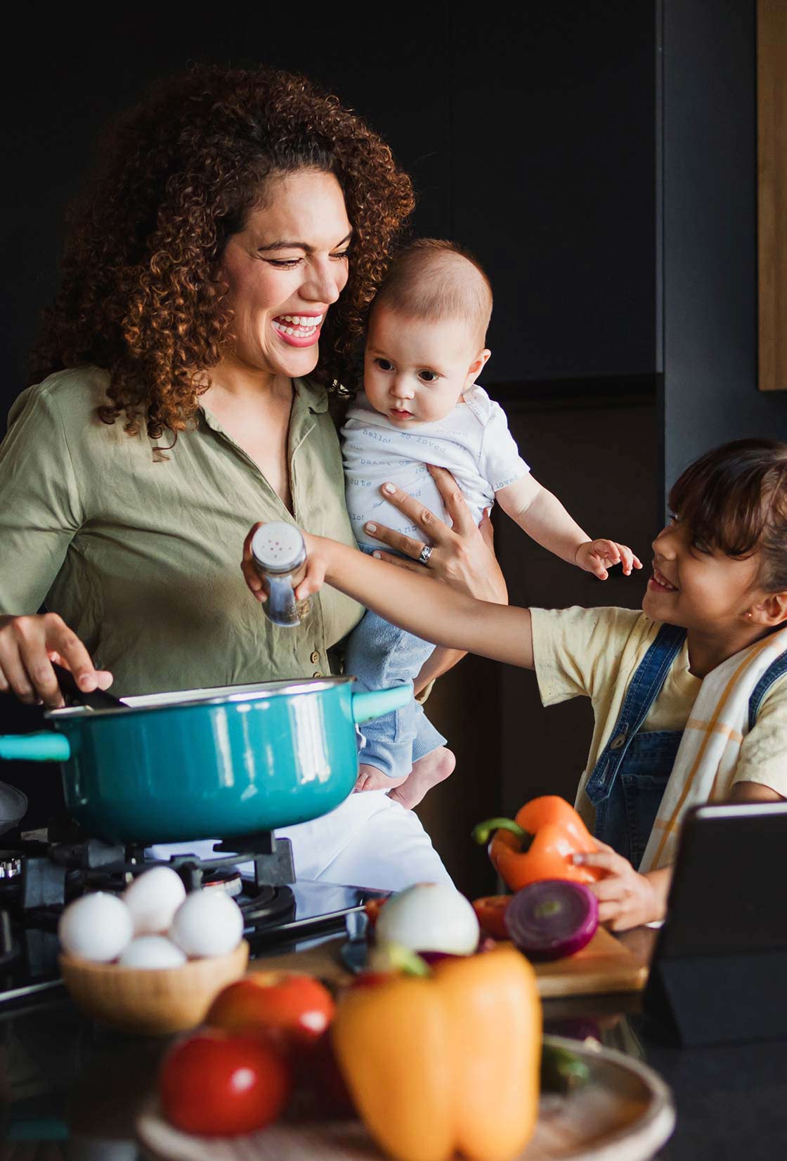 Hispanic mother and her two children preparing a meal in the kitchen.