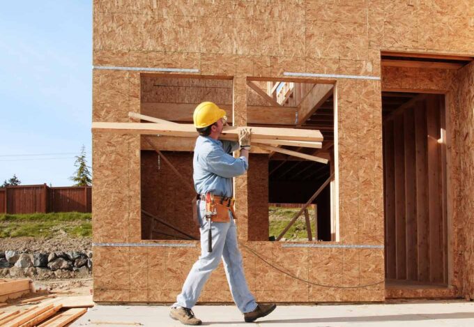 Worker carries wood for a home construction project.