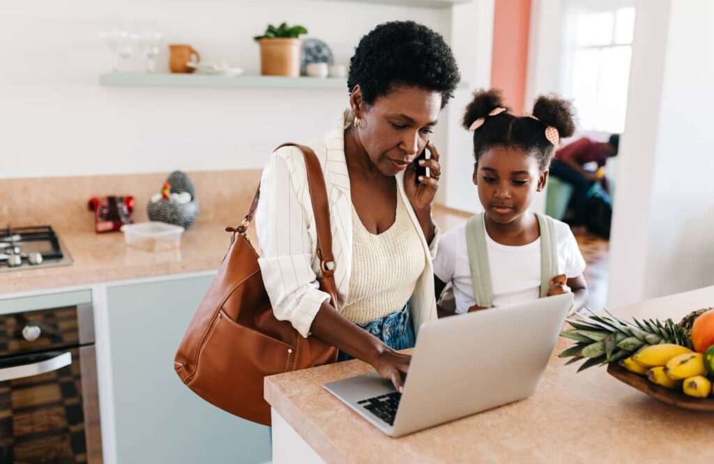 Daughter and mother stand in front of laptop in their kitchen while researching down payments.