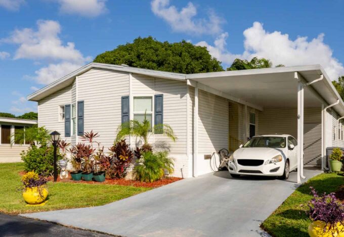 Outside of manufactured home with a car sitting in carport.