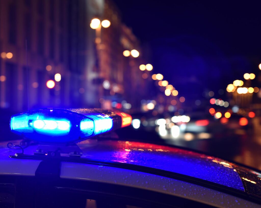 Close up of a police car siren on the scene with law enforcement officers in the line of duty.
