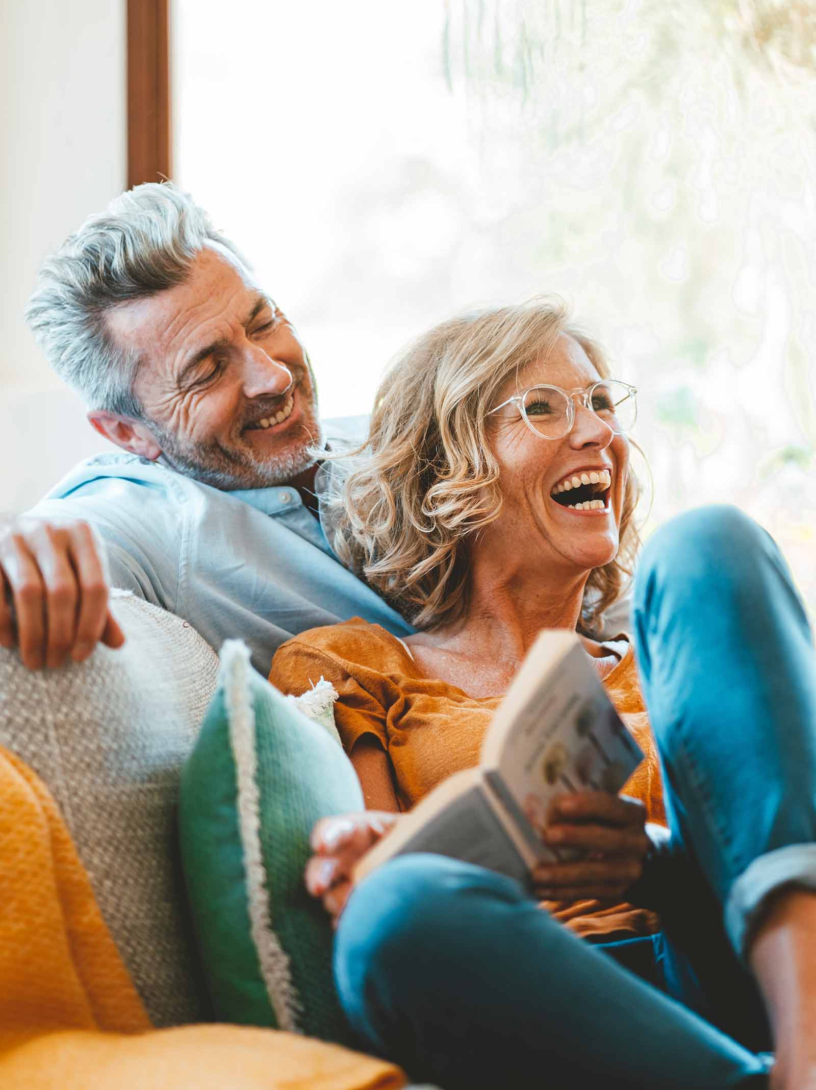 Retired couple relaxes together on the couch in a home that they have used a HECM loan to tap into their home equity.