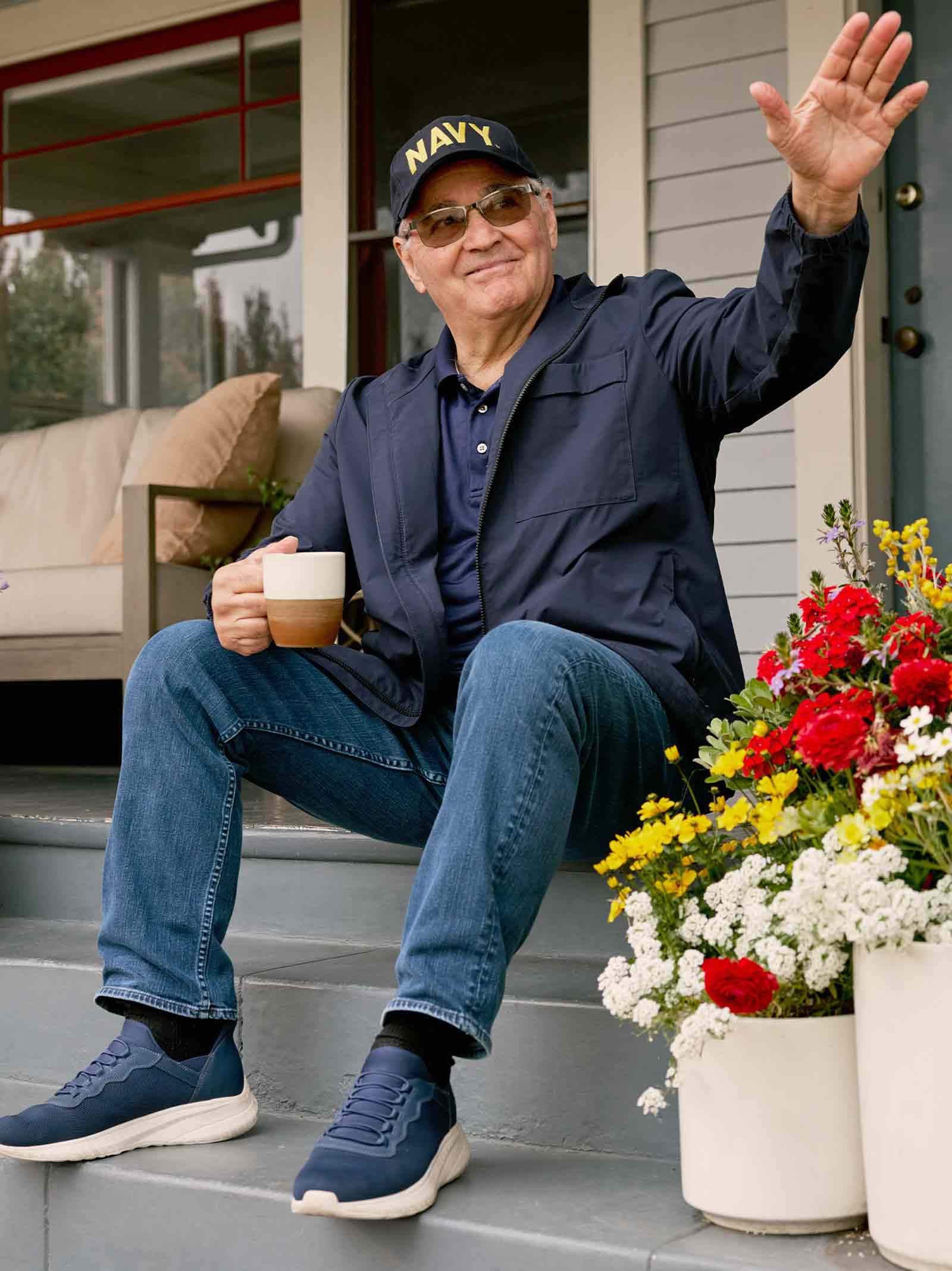 Navy veteran holding coffee cup sits on front porch of home refinanced using a VA IRRRL.